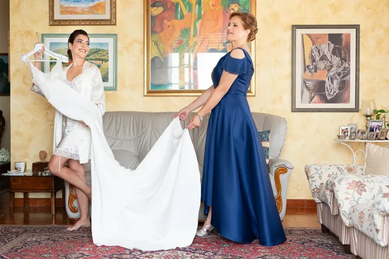 La sposa viene aiutata dalla mamma ad indossare l'abito