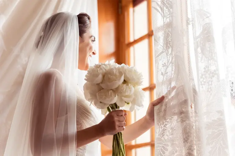 ritratto di sposa che sorride davanti ad una finestra aperta